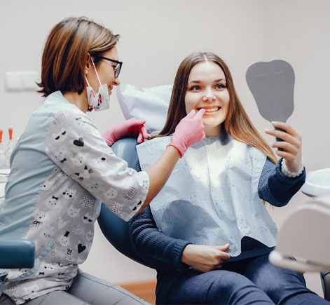 Dental hygienist showing young female patient teeth examination results in modern clinic office.