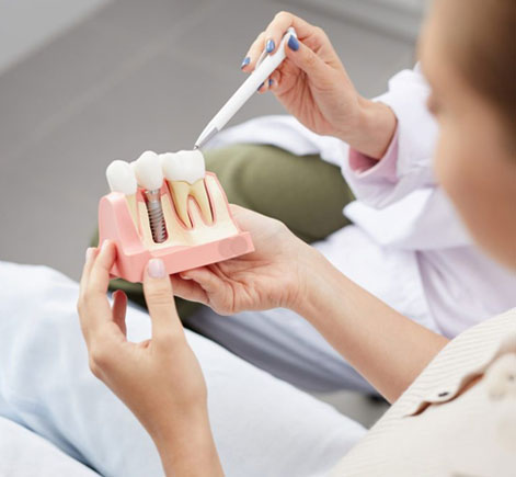 Dentist showing patient dental implant model during consultation in dental office