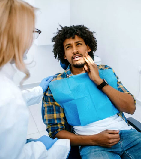 Dentist examining male patient's jaw and teeth in clinical office setting.