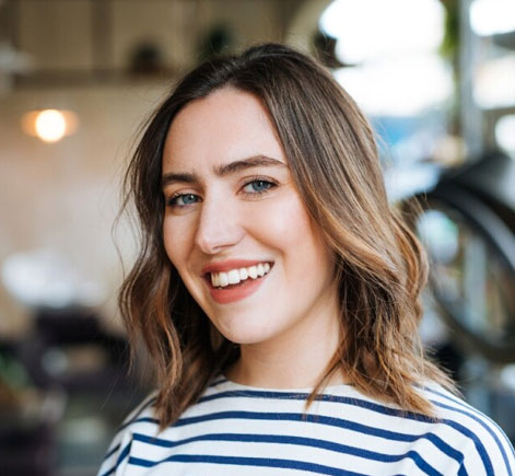 Smiling woman in striped shirt at Calistoga dental office, indoor professional setting with blurred background.