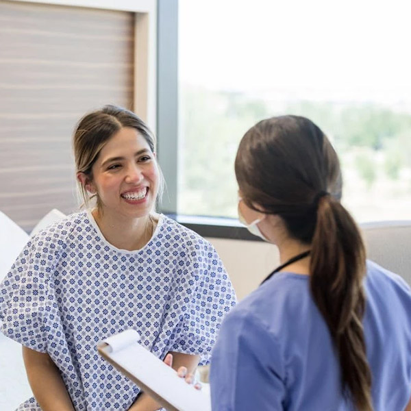 Dental professional in blue scrubs consulting with female patient in clinical office setting.