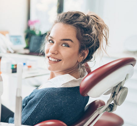Smiling woman in dental chair at modern dental office during routine checkup or consultation.